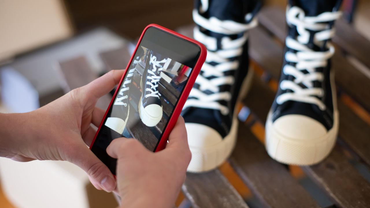 Vendedora fotografando tênis com o celular para publicar no Instagram da loja