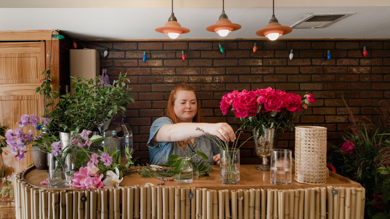 Dona de floricultura organizando flores no balcão da loja